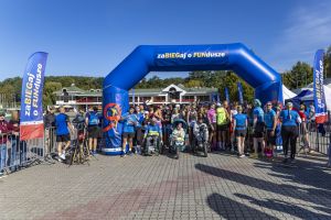 Start biegu zaBIEGaj o FUNdusze pod niebieską bramą dmuchaną z wózkarzami w pierwszym szeregu uczestników.