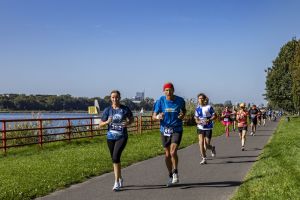 Biegaczka z numerem 362 i mężczyzna z numerem 414 w czerwonej opasce; w tle uczestniczka w różowej tutu.