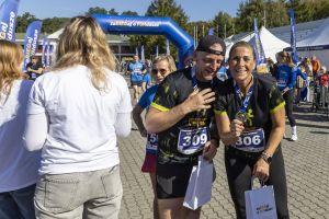 Para w czarno-żółtych koszulkach z numerami 306 i 309 z medalami i torbami śmieje się przy bramie finiszu.