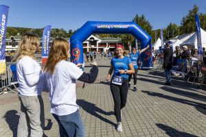 Biegaczka z numerem 383 w czerwonej czapce dobiega do mety, za nią uczestniczka z numerem 333 unosi ręce.