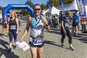 Biegacz Grodziskiego Klubu Biegacza z numerem 728 pokazuje medal i torbę z logo zaBIEGaj o FUNdusze.