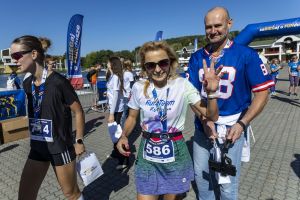 Biegaczka Run Team z numerem 586 macha do kamery obok mężczyzny w niebieskiej koszulce z numerem 88.