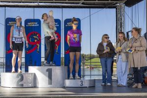 Podium kobiet nad Maltą: zwyciężczyni z dzieckiem na rękach, druga z numerem 245, trzecia w fioletowej koszulce.