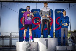 Podium męskie zaBIEGaj o FUNdusze: zwycięzca w szarej kurtce Nike, drugie miejsce numer 211, trzeci w niebieskiej.