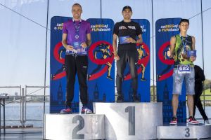 Trzech mężczyzn na podium nad Maltą: środkowy w czapce i koszulce Istanbul, boczni z medalami i kopertami.