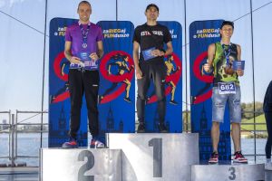 Laureaci męskiej kategorii na podium; zawodnik na trzecim stopniu pokazuje kciuk w górę z medalem na szyi.