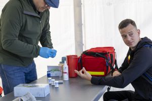Badanie profilaktyczne przy czerwonej torbie ratunkowej; personel medyczny przygotowuje materiał na tacy.