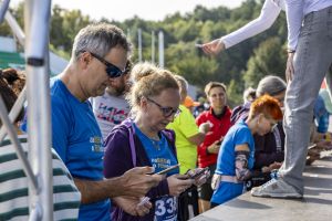 Para uczestników w niebieskich koszulkach zaBIEGaj o FUNdusze sprawdza telefony przy stanowisku na Malcie.